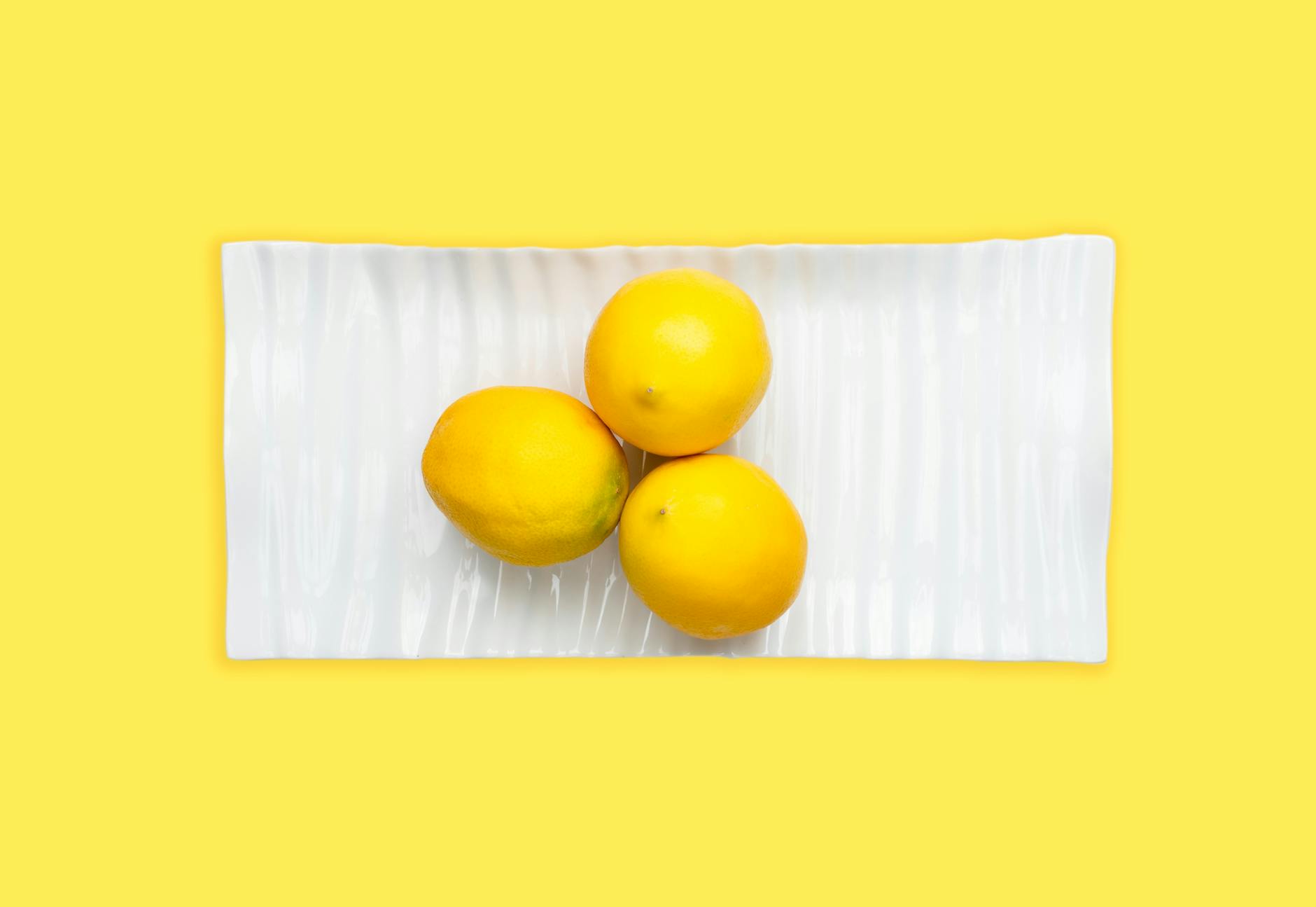 Fresh lemons on a white plate with a vibrant yellow background, symbolizing the sensory shift of arousal during midlife