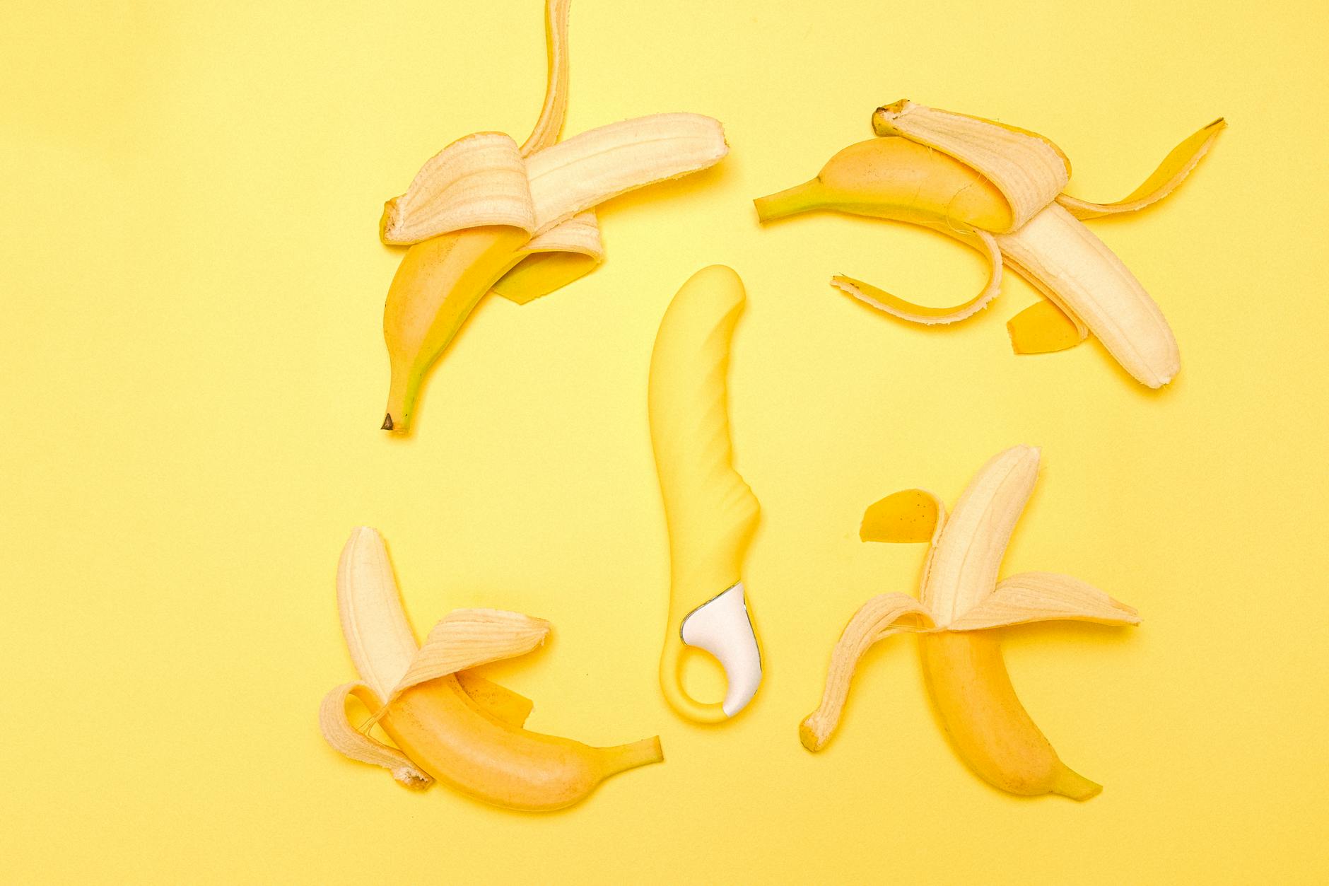 Yellow silicone lemon vibrator surrounded by fresh lemons on bright background