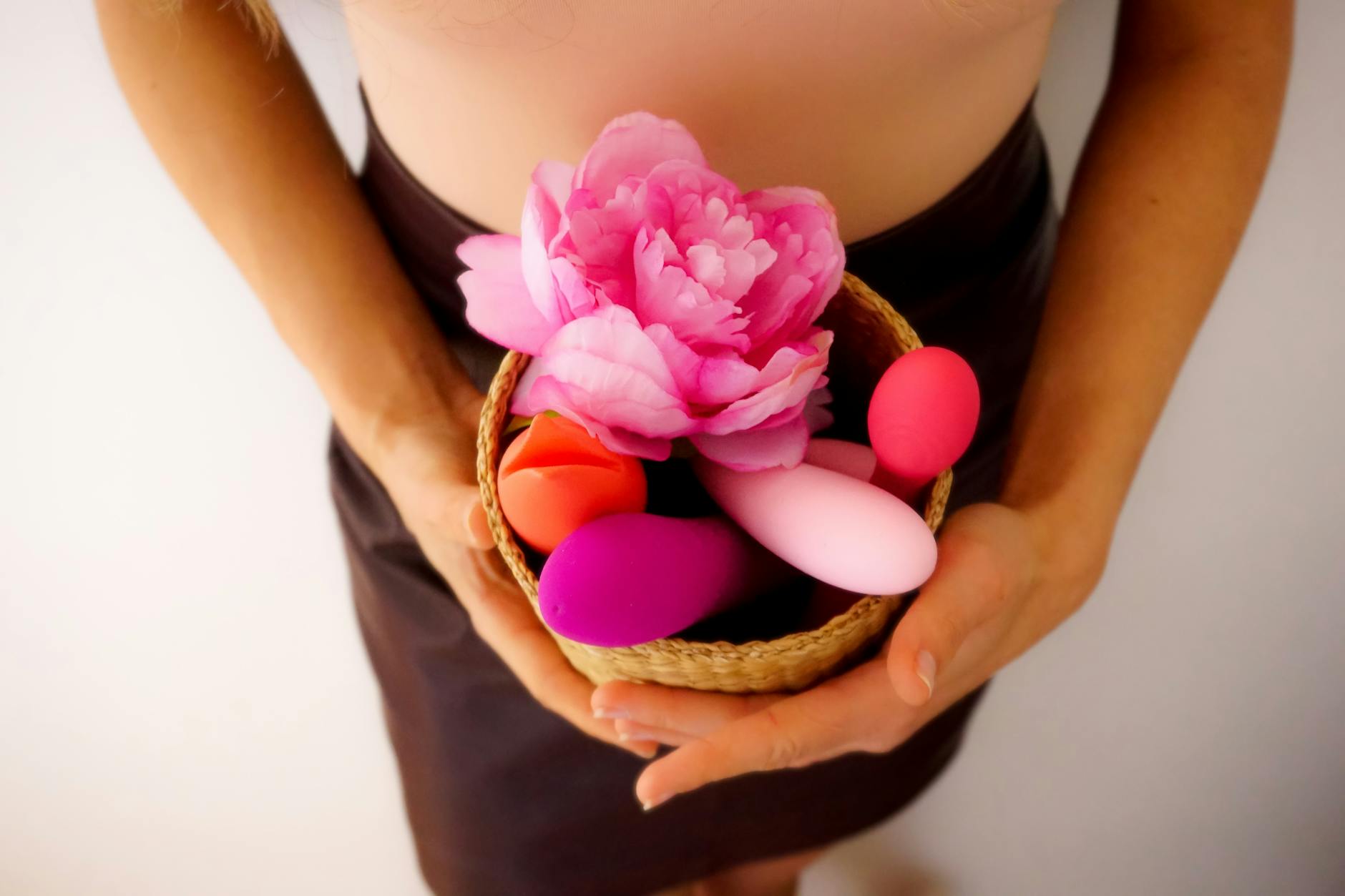Woman holding two silicone vibrators, contemplating sensation and pleasure